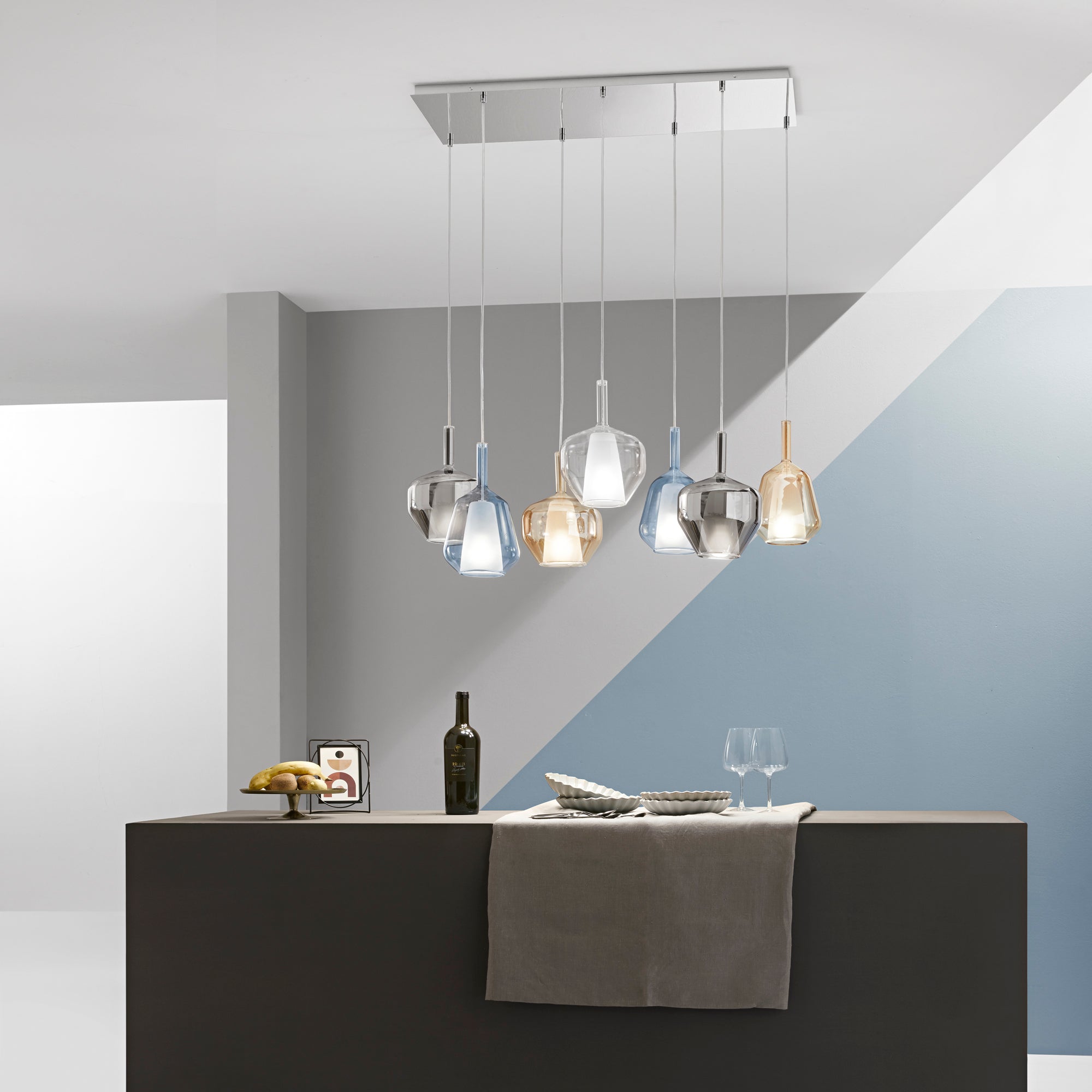 Lampadario a grappolo moderno con elementi in vetro colorato sopra un tavolo da pranzo rettangolare.