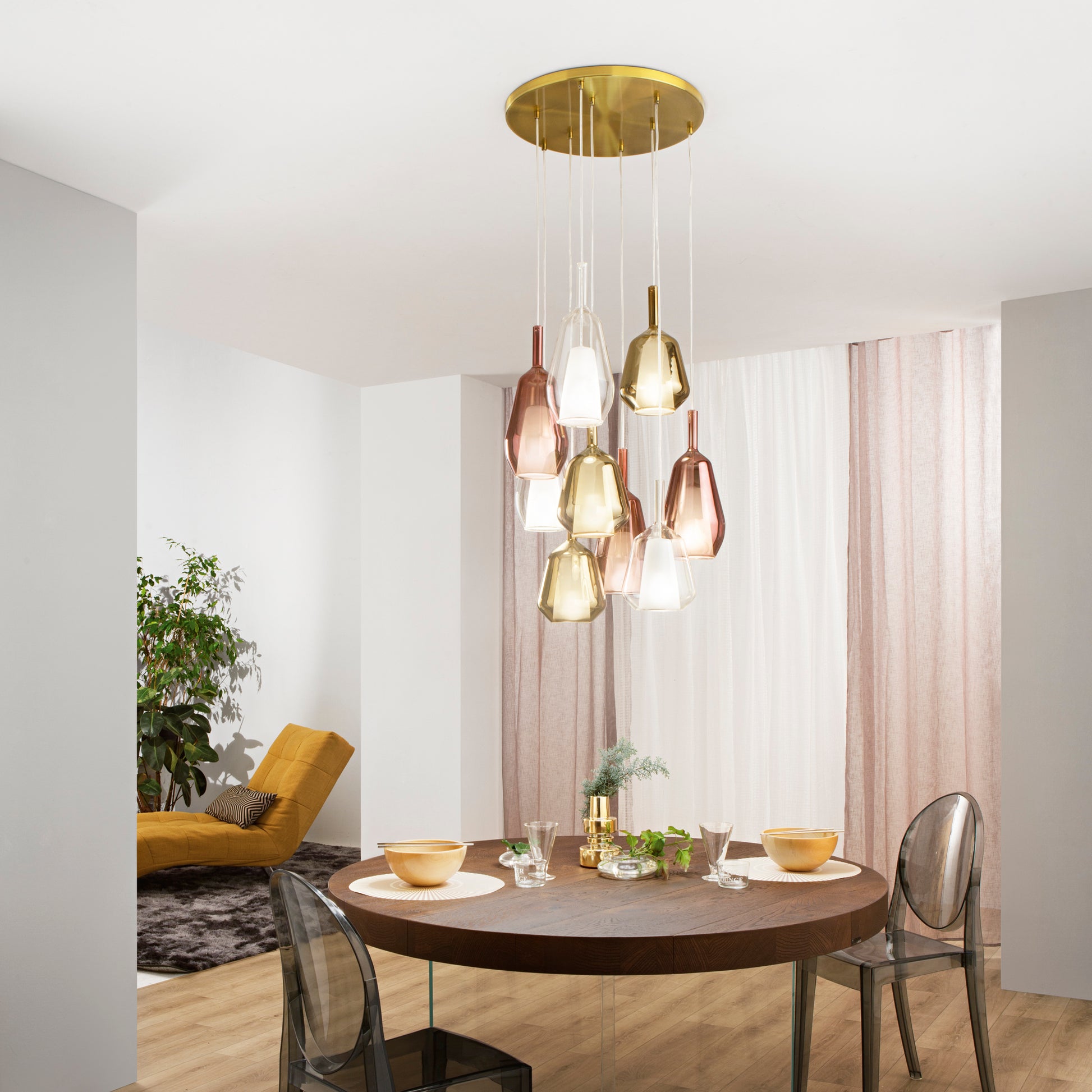 Lampadario a grappolo moderno con elementi in vetro colorato sopra un tavolo da pranzo circolare.