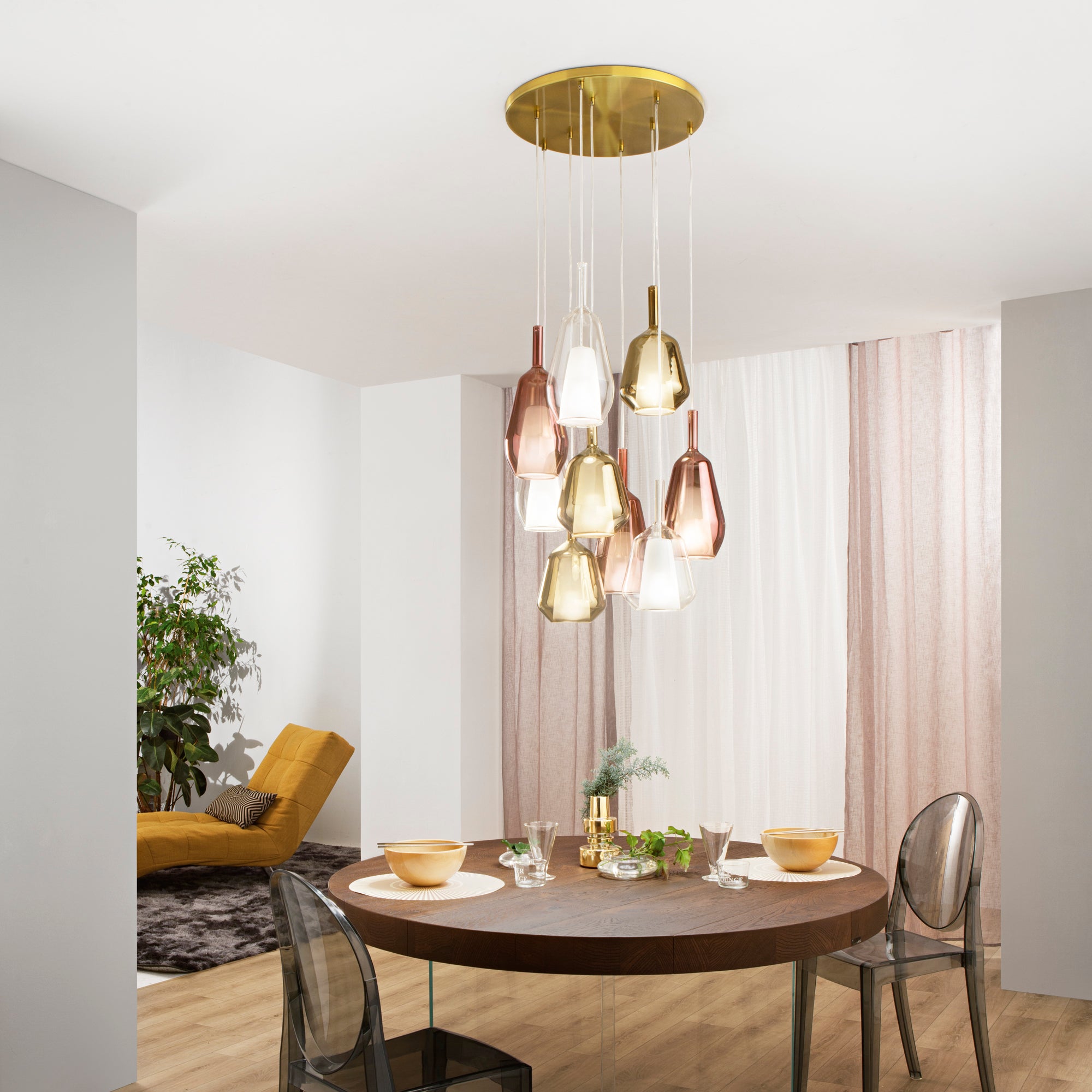Lampadario a grappolo moderno con elementi in vetro colorato sopra un tavolo da pranzo circolare.