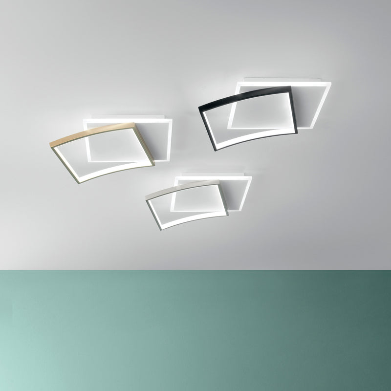 Plafoniera LED moderna composta da tre moduli quadrati leggermente curvati e sovrapposti, con struttura in metallo disponibile in diverse finiture (bianco, nero e oro), montata su soffitto chiaro con luce diffusa e design geometrico contemporaneo.